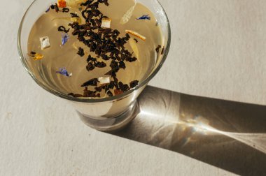 Siyah çay yaprakları bir saydam mavi çiçekler, portakal kabuğu ile