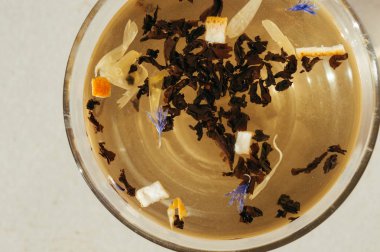 Siyah çay yaprakları bir saydam mavi çiçekler, portakal kabuğu ile