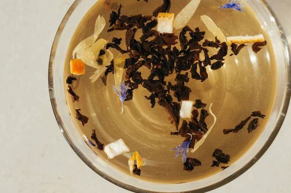 Siyah çay yaprakları bir saydam mavi çiçekler, portakal kabuğu ile