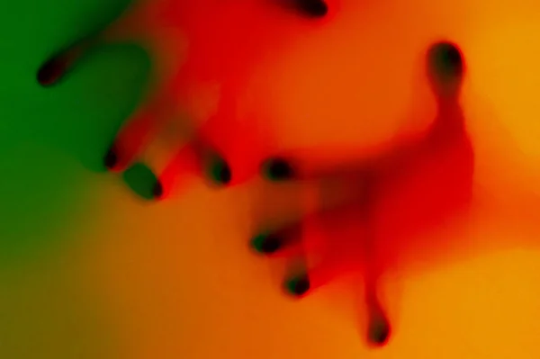 Hands in orange and green neon light gradient behind white surface. Foggy blurred effect for different concept ideas. — Stock Photo, Image