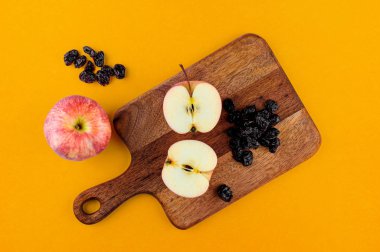 Tahtada kırmızı elmalar ve kurumuş kızılcıklar. Kalın sarı kağıt arka plan. Üst görünüm düz konum. Metin şablonu için boşluk