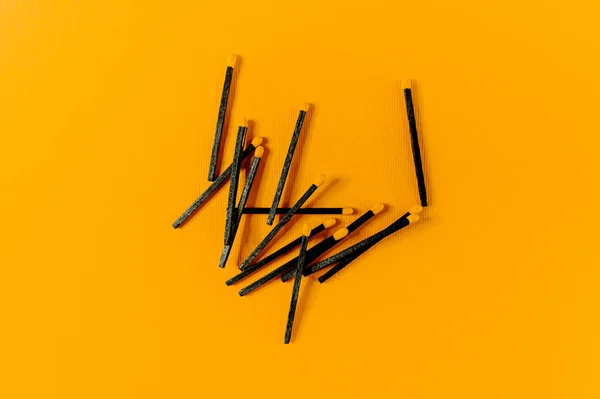 Black wood matches with yellow heads on bold yellow background. — Stock Photo, Image