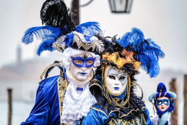 Venedik, İtalya 16 Şubat: Siyah carnaval maskeyle uzun tüylü şapka, kırmızı dudaklar ve hassas oyma ayakta altında Köprüsü, Venedik, İtalya.