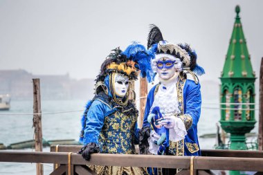 Venedik, İtalya 16 Şubat: Siyah carnaval maskeyle uzun tüylü şapka, kırmızı dudaklar ve hassas oyma ayakta altında Köprüsü, Venedik, İtalya.