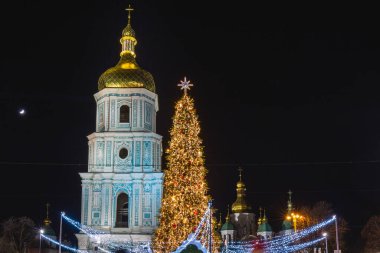 Kiev 'de geceleri ışıkları açık olan bir Noel ağacı. Arkadaki Sophia Katedrali. Kiev, Ukrayna 'da yeni yıl kutlaması. Noel pazarı.