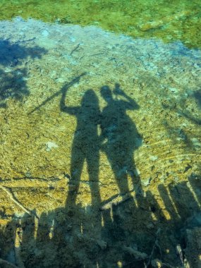 Hırvatistan 'ın Plitvice Gölleri' ndeki dünyanın en şaşırtıcı yerlerinden birinin şelaleleri yakınındaki turistlerin gölgeleri. Gerçekten bakire ve doğanın harika bir parçası..