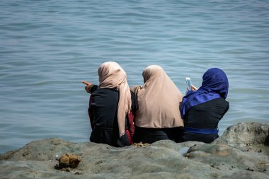 Kumsalda giyinmiş Müslüman kadınlar. Ölü deniz, İsrail 'de vücut bakımı.