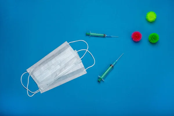 Green syringes and surgical mask with rubber ear straps. Coronavirus 2019-ncov epidemic concept. Procedure mask from bacteria. Protection concept.