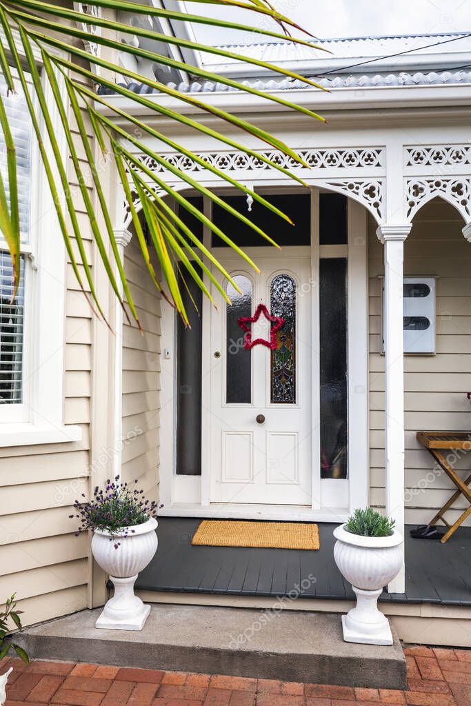 Side wall of vintage wooden building with palm tree and Christmas star on the door at Auckland, New Zealand.