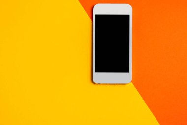 Dümdüz yatıyordu. Bilgisayar kırmızı ve sarı arka planda, akıllı telefonlu. İş konsepti. Boşluğu kopyala.