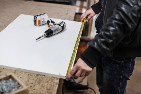 Монтаж мебели из ДСП, используя беспроводную отвертку, крупным планом.