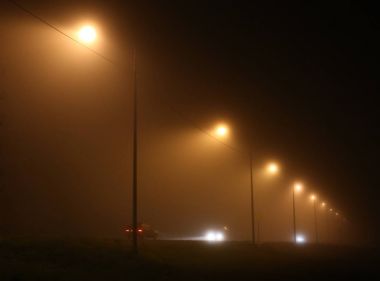 Gece yoğun sis içinde şehir. Karanlık bir sokakta kalın duman.