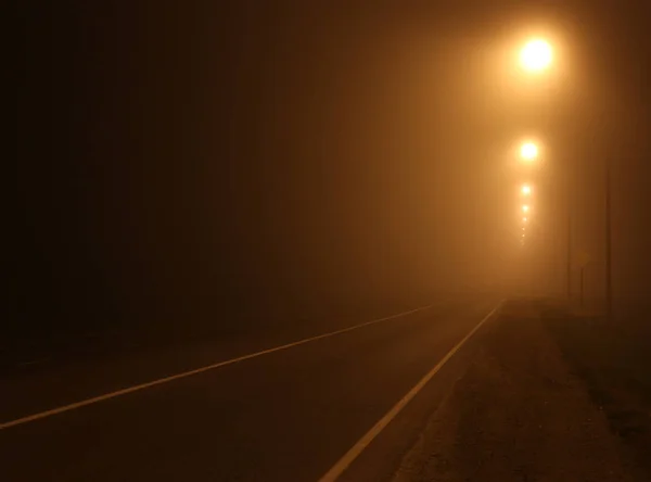 Gece yoğun sis içinde şehir. Karanlık bir sokakta kalın duman.