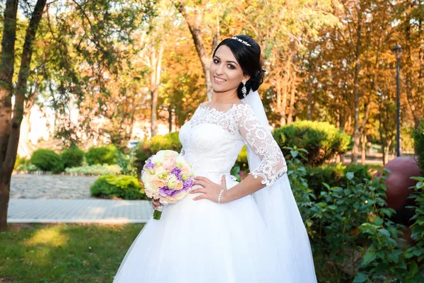 美丽的新娘在婚礼的日子在秋天森林的背景与一个美丽的花束 — 图库照片