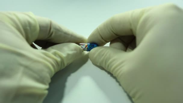 Mani in guanti medici, capsula aperta con palline di colore — Video Stock
