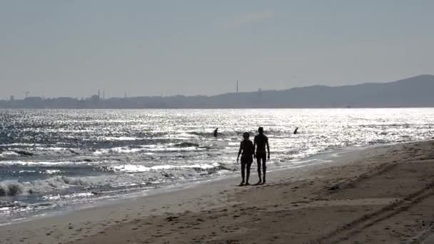 Ανθρώπους που περπατούν στην παραλία με Piombino στο παρασκήνιο — Αρχείο Βίντεο