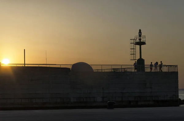 Silhouet van mensen op de pier bij de zonsondergang — Stockfoto