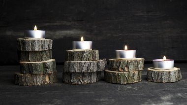 Christmas candles burning, decoration with wooden logs resting on wooden background clipart