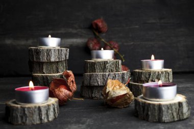 Christmas candles burning, decoration with wooden logs resting on wooden background clipart