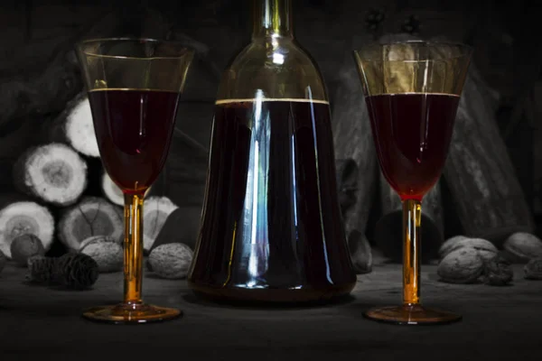 Red Wine Vintage Bottle and Glasses Resting On Wooden Table Against Christmas Background With Wood logs and Pine Branches