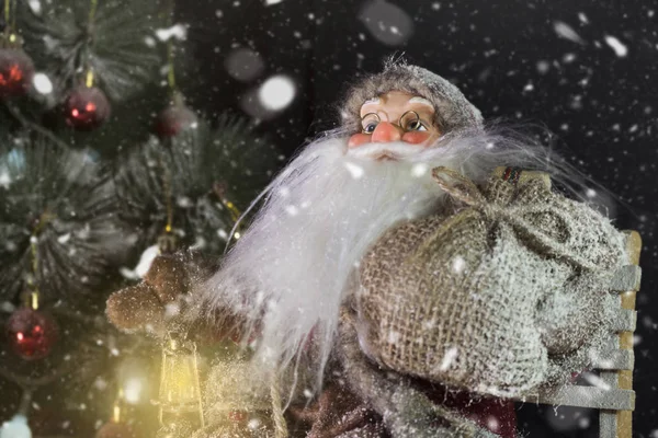 Papai Noel ao ar livre ao lado da árvore de Natal na neve levando presentes para as crianças. Feliz Natal & Conceito de véspera de Ano Novo — Fotografia de Stock