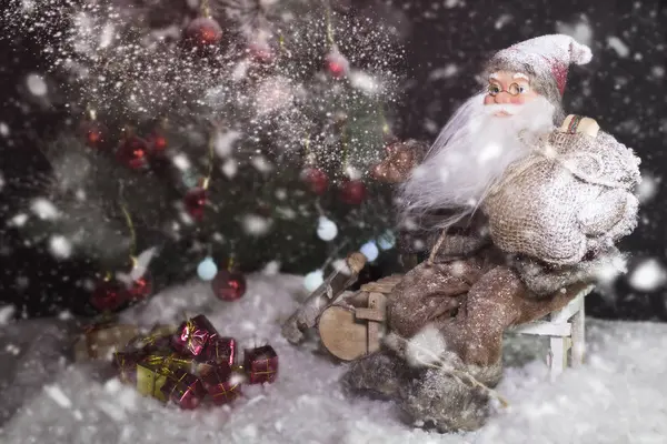 Papai Noel ao ar livre ao lado da árvore de Natal na neve levando presentes para as crianças. Feliz Natal & Conceito de véspera de Ano Novo — Fotografia de Stock