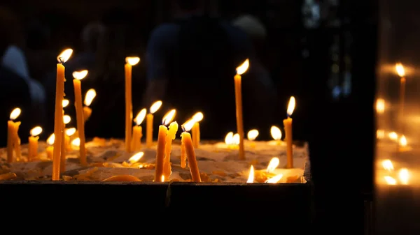 Свічки спалюються в церкві і відбиваються від стіни — стокове фото
