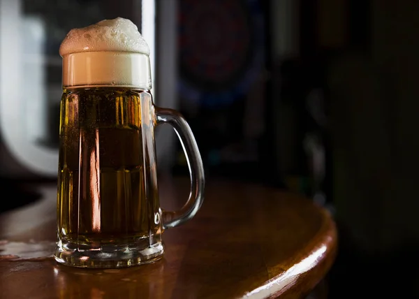 Cerveza en una taza con espuma Descansando en una superficie de madera con espacio en blanco para un logotipo o texto — Foto de Stock