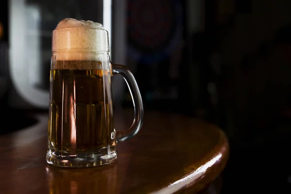 Cerveza en una taza con espuma Descansando en una superficie de madera con espacio en blanco para un logotipo o texto — Foto de Stock