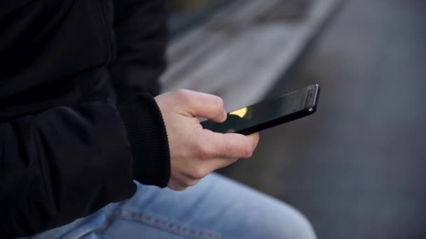 Άνθρωπος Κάθεται Στο Bench Στην Πόλη Χρησιμοποιώντας Smartphone Στο Αστικό — Αρχείο Βίντεο