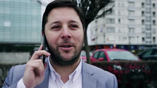 Geschäftsmann Der Draußen Vor Dem Bürogebäude Mit Dem Smartphone Spricht — Stockvideo