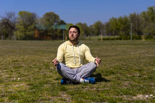 Man practicing Yoga in park. Meditation and zen relaxation in nature