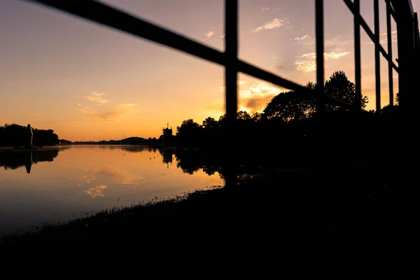 黄金の時間で湖の夕日フェンスを通って見える — ストック写真