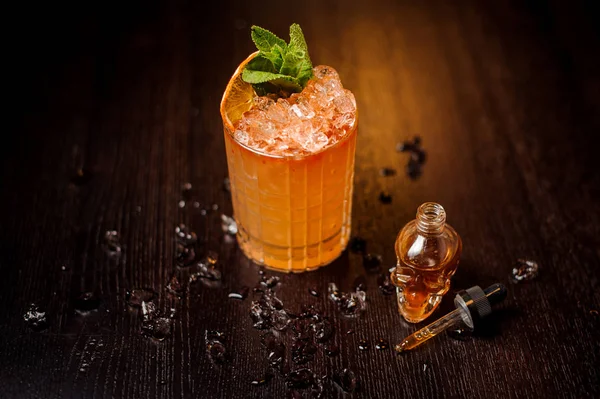 Piccola bottiglia a forma di teschio e cocktail all'arancia — Foto Stock
