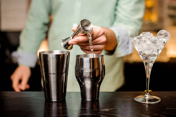 Primo piano delle mani del barista versare bevanda in un jigger per preparare un cocktail — Foto Stock