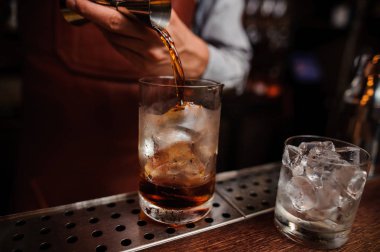 Barmen el dökülen içki dolu kokteyl bardağına fincan ölçme