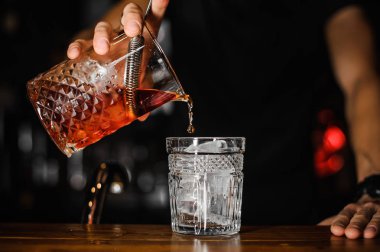 Barmen dökme parlak kırmızı alkol kokteyl bardağına yakın çekim