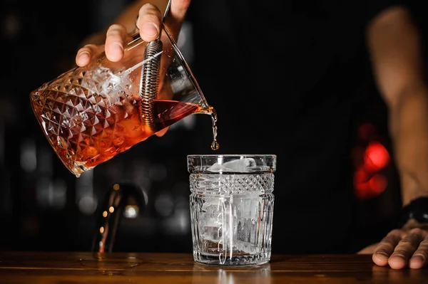 Barmen dökme parlak kırmızı alkol kokteyl bardağına yakın çekim