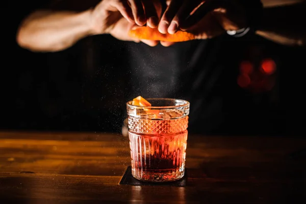 Barman met cocktail en oranje schil voorbereiding cocktail in bar — Stockfoto