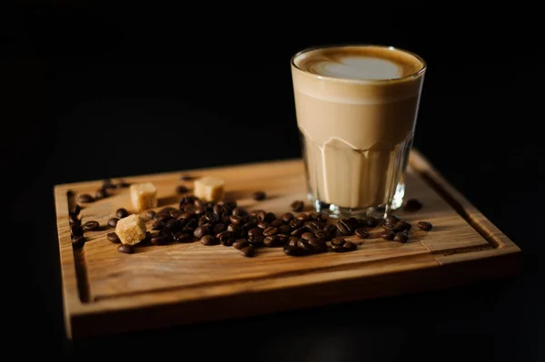 Ένα φλιτζάνι καφέ με κόκκους καφέ και ζάχαρη από ζαχαροκάλαμο σε ένα ξύλινο ταμπλό με. — Φωτογραφία Αρχείου