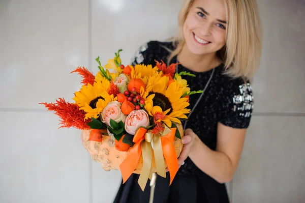 Flores de otoño en manos de la mujer. Calabaza, girasoles y otras flores — Foto de Stock