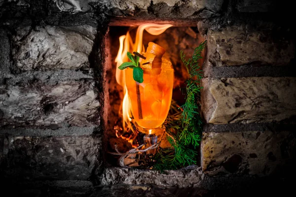 Гарячий апельсиновий напій на фоні полум'я — стокове фото