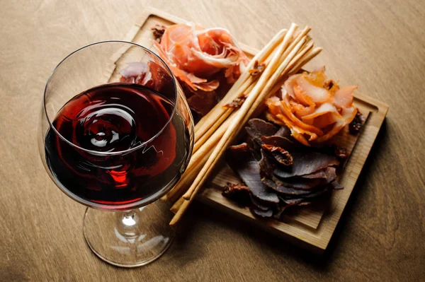 Bardak kırmızı SEK şarap ve çeşitli ahşap tahta üzerinde tedavi et