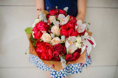 Çiçekçi elinde bir buket çiçek tutuyor.