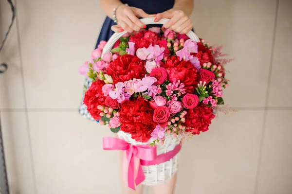 Frau mit einem schönen Weidenkorb voller Blumen — Stockfoto