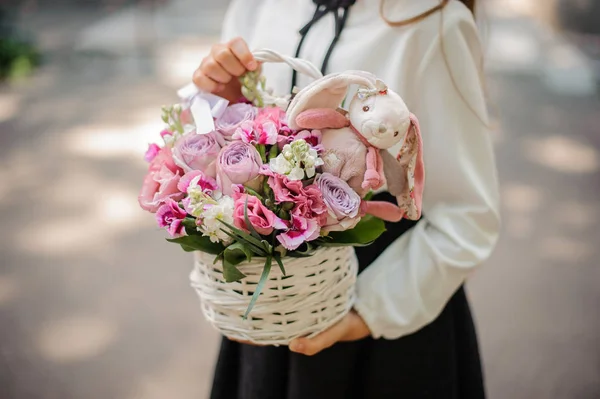 Girl holding a beautiful wicker basket of flowers with toy — Stock Photo, Image