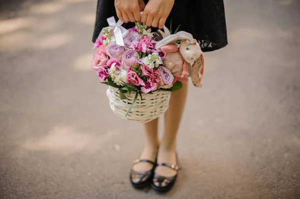 Ragazza che tiene un bellissimo cesto di vimini di fiori con coniglio giocattolo — Foto Stock