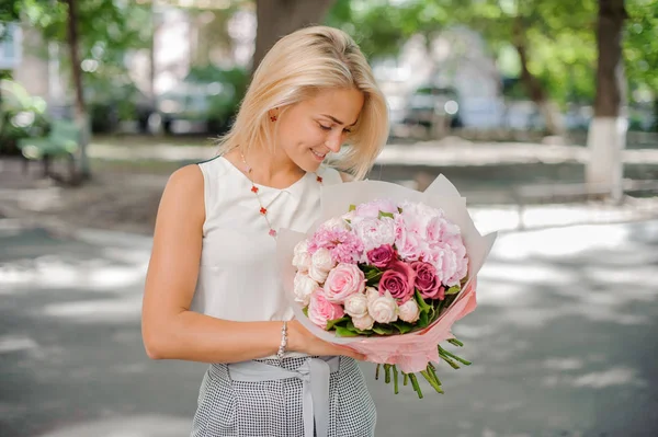 Jolie femme blonde tenant une belle composition de fleurs — Photo