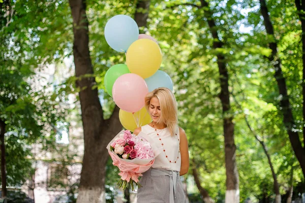 Birthday girl with a bouquet of pretty flowers and balloons