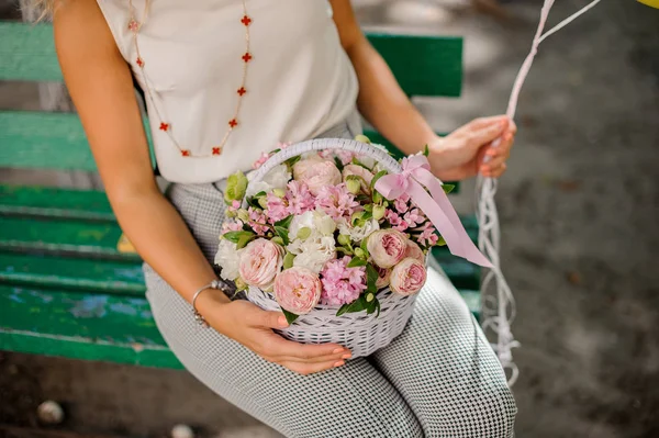 Mulher segurando uma bela composição de flores em cesta de vime — Fotografia de Stock